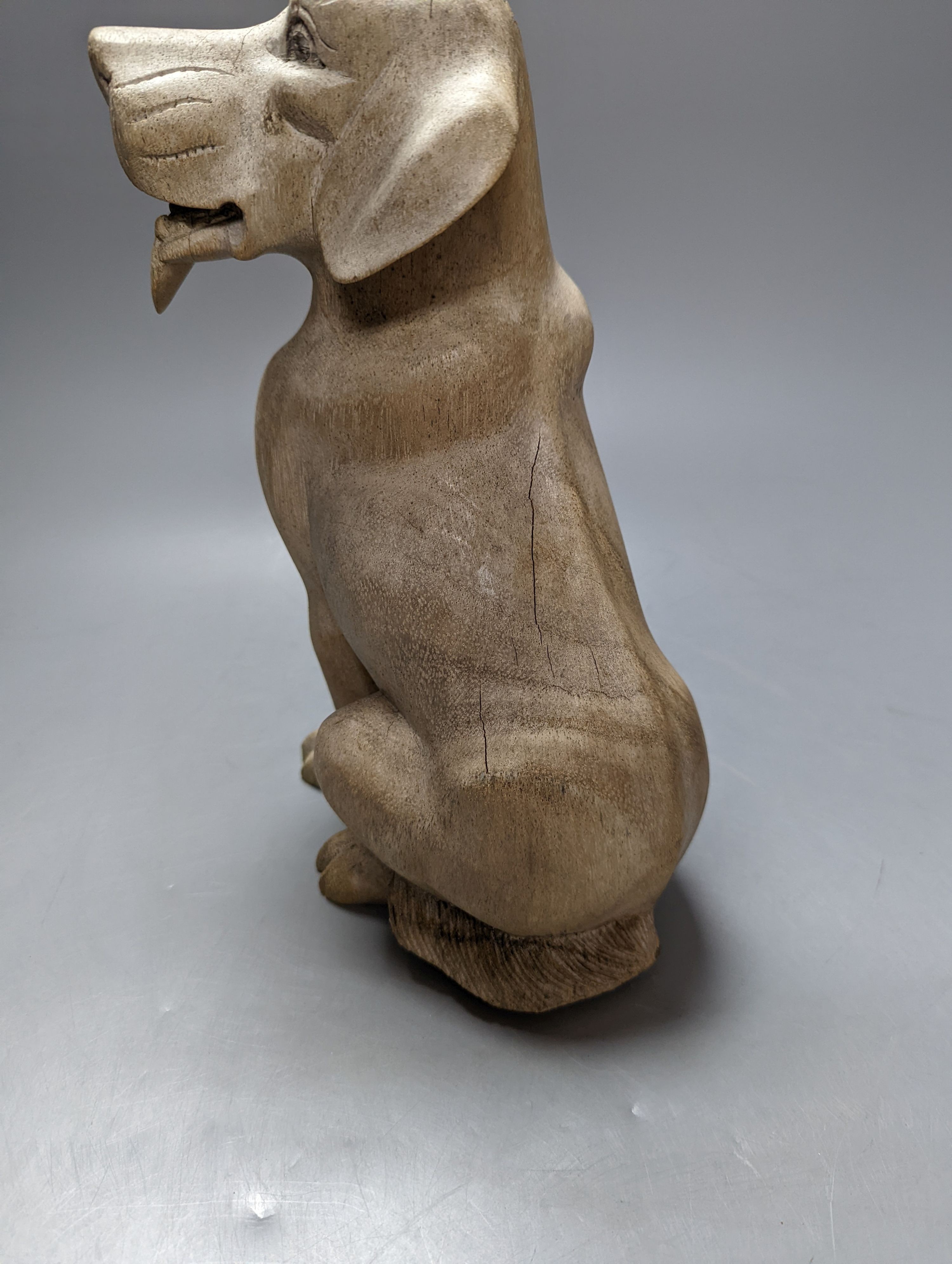 A carved wood model of a seated dog 29cm